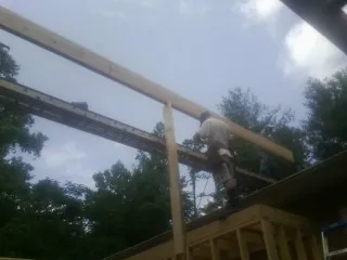 Carpenter setting a ridge beam over a new addition frame — Ice Dam Removal by Roofing Brothers in New Auburn