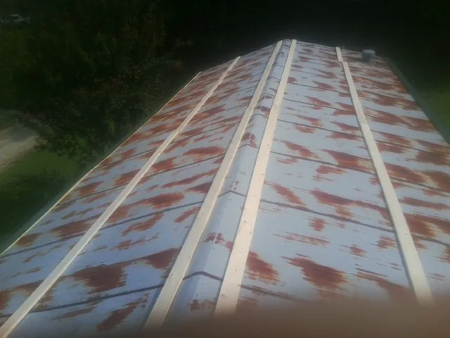 Rusted metal roof panels with new wood purlins before replacement — Storm Damage Roof Repair in New Auburn by Roofing Brothers