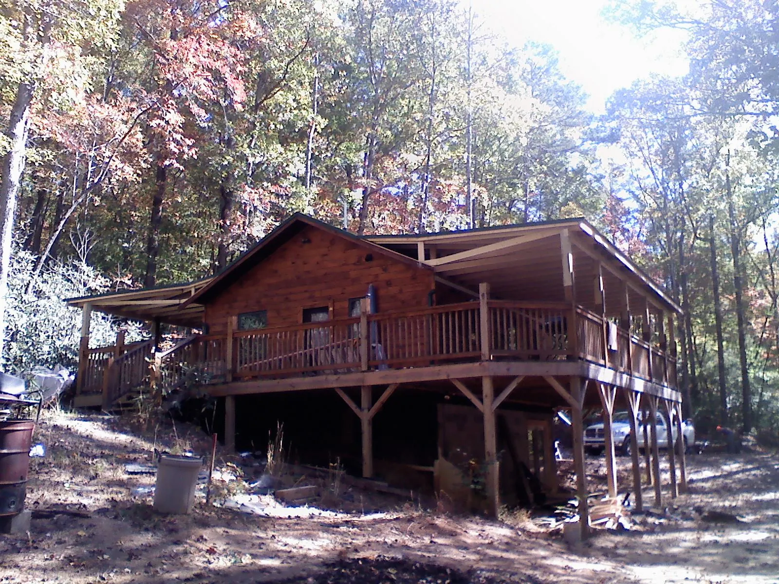 Log cabin with a wraparound porch and metal roof in the fall in New Auburn