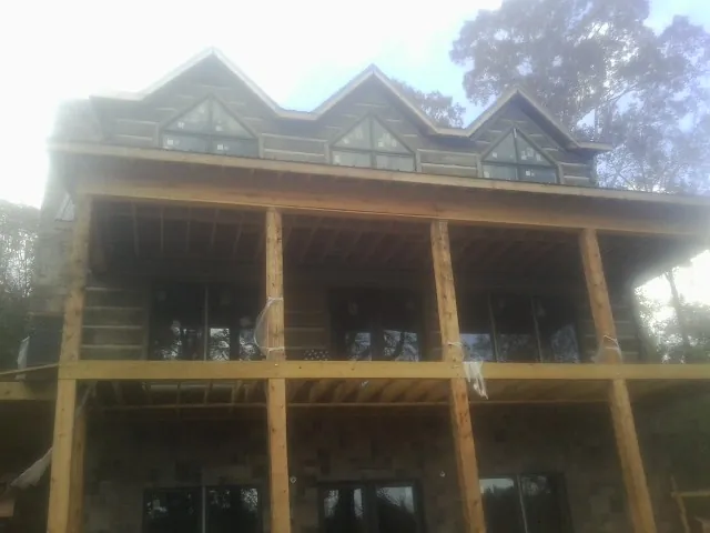 Dormers and porch framing on a large log home under construction — Roof Coating work by our crew in New Auburn