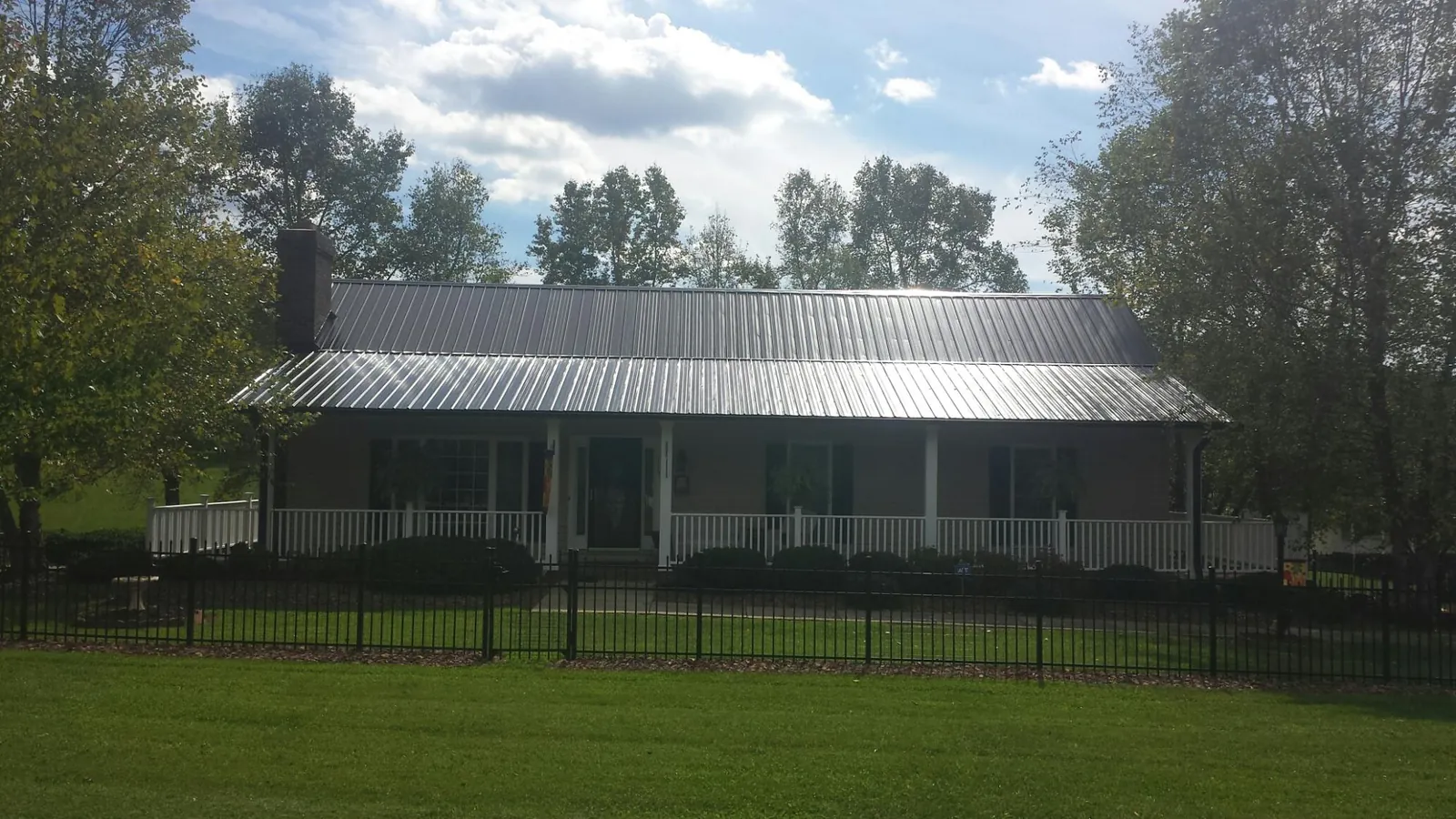 Gray metal roof on a brick ranch with a full width front porch — Gutter Guard Installation work by our crew in New Auburn
