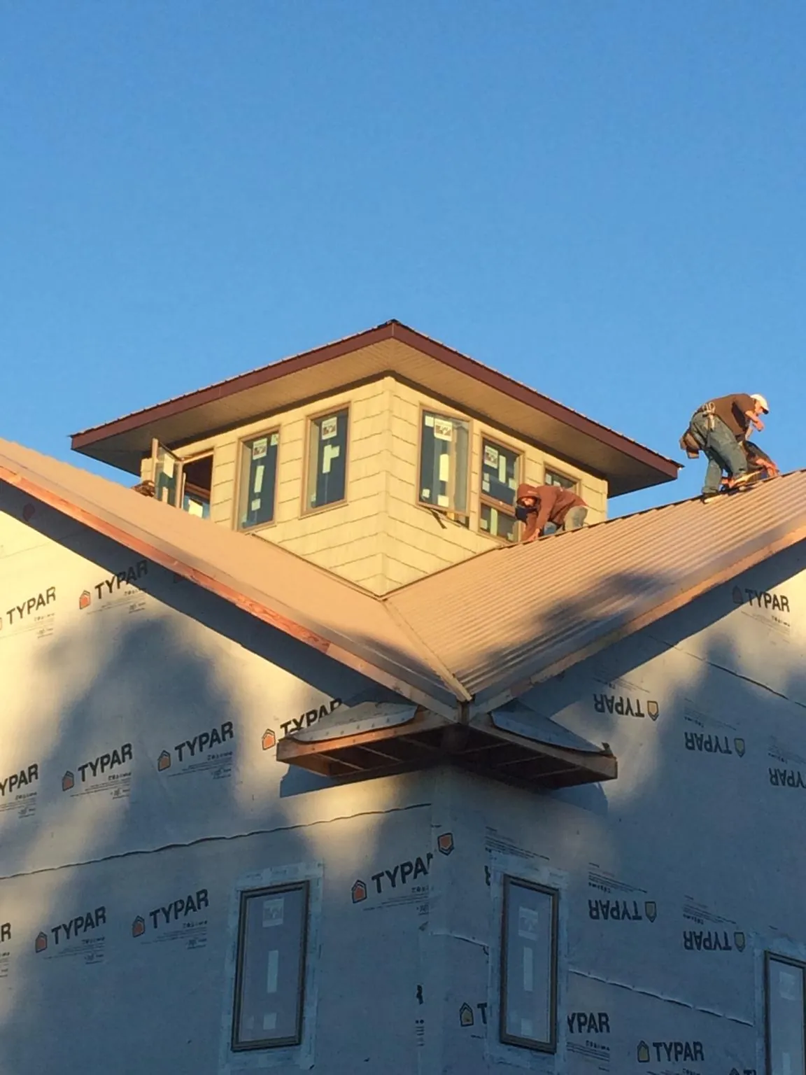 Roofers working around a rooftop cupola on a new metal roof at sunset — Roof Waterproofing in New Auburn by Roofing Brothers
